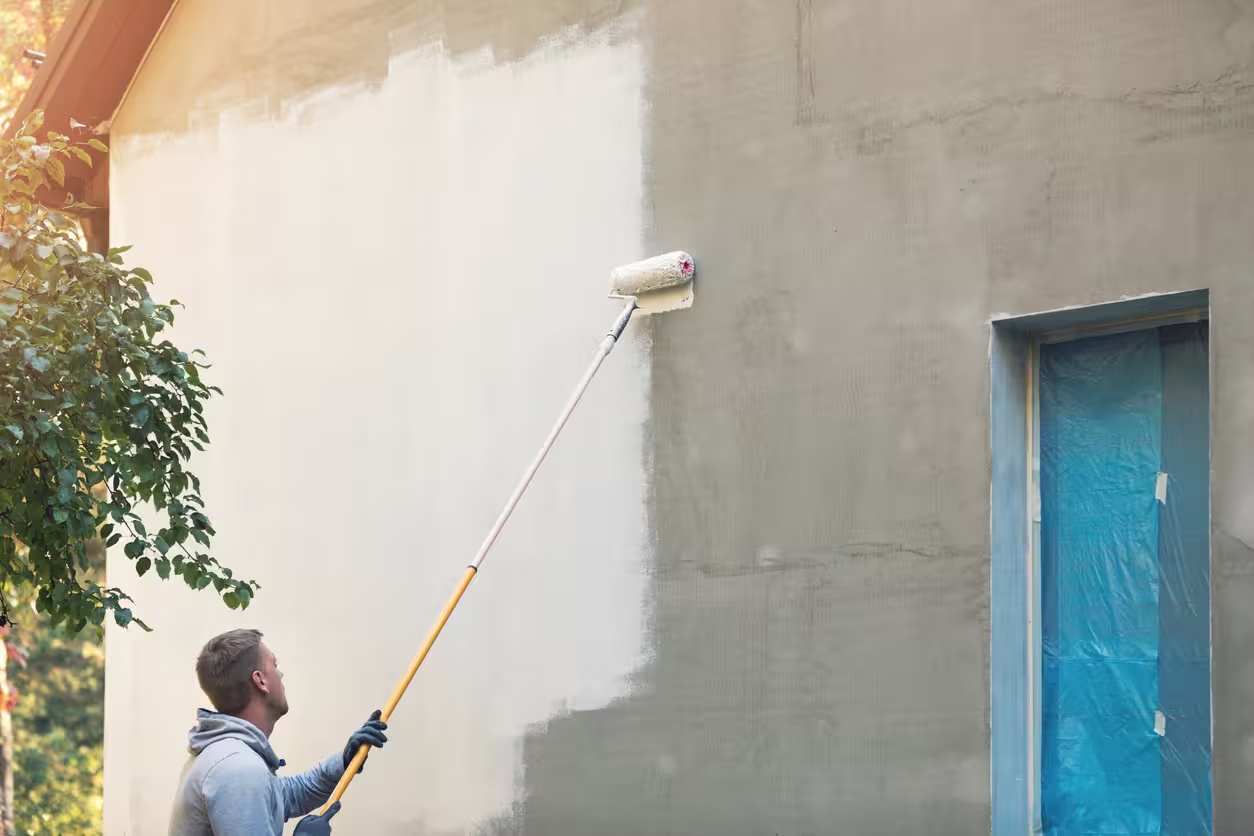 Peintre peignant façade d'une maison