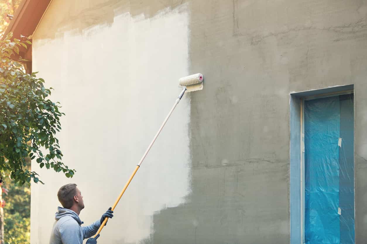 Peintre peignant façade d'une maison