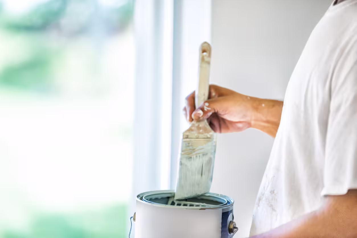 Zoom sur main tenant un pinceau et pot de peinture