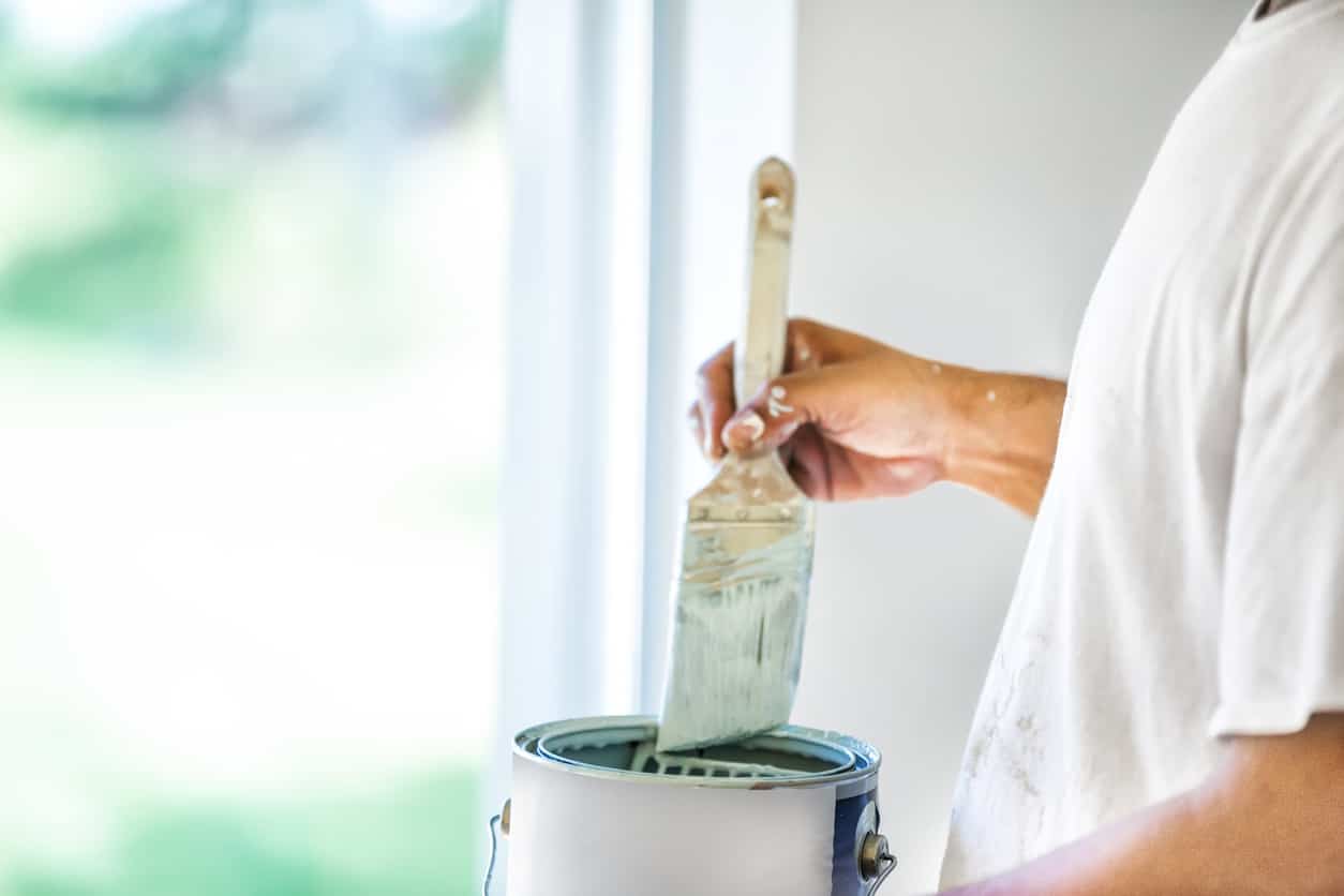 Zoom sur main tenant un pinceau et pot de peinture